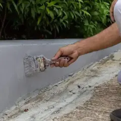 Malowanie betonowego murku na zewnątrz. Szara farba do betonu na zewnątrz zapewnia trwałą ochronę.