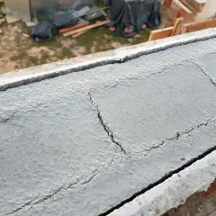 Pęknięcia na świeżym betonie wieńca budowlanego, widoczny pręt kotwiący.