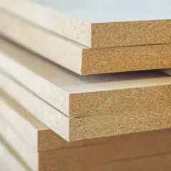 Stos płyt MDF, materiału drewnopochodnego, gotowego do obróbki.