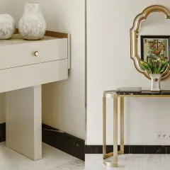 Elegancka konsola z marmurowym blatem i złotymi nogami, ozdobiona wazonem z tulipanami i flakonem perfum. Obok, biała komoda z dwoma wazonami i książką "Art Deco".