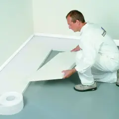 Pracownik układa biały styropian na podłogę, przygotowując izolację. To dobry wybór, jaki styropian na podłogę wybrać.