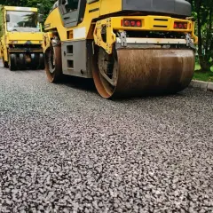 Walec drogowy wyrównuje świeżo położoną pospółkę, przygotowując drogę do dalszych prac.