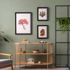 Inspirujące kolory ścian do salonu: zieleń, morskie akcenty na obrazach i naturalne drewno.