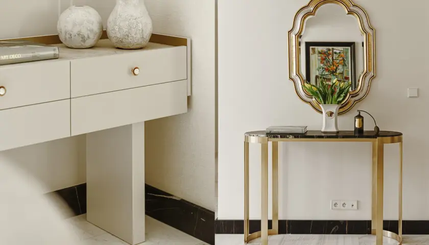 Elegancka konsola z marmurowym blatem i złotymi nogami, ozdobiona wazonem z tulipanami i flakonem perfum. Obok, biała komoda z dwoma wazonami i książką "Art Deco".