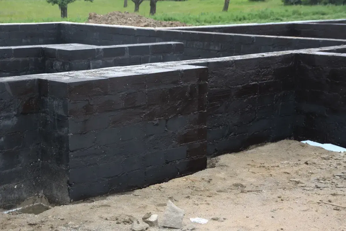Fundament z czarnej cegły, przygotowany do dalszych prac. Widać, że próbowano go disprobit, by zabezpieczyć przed wilgocią.