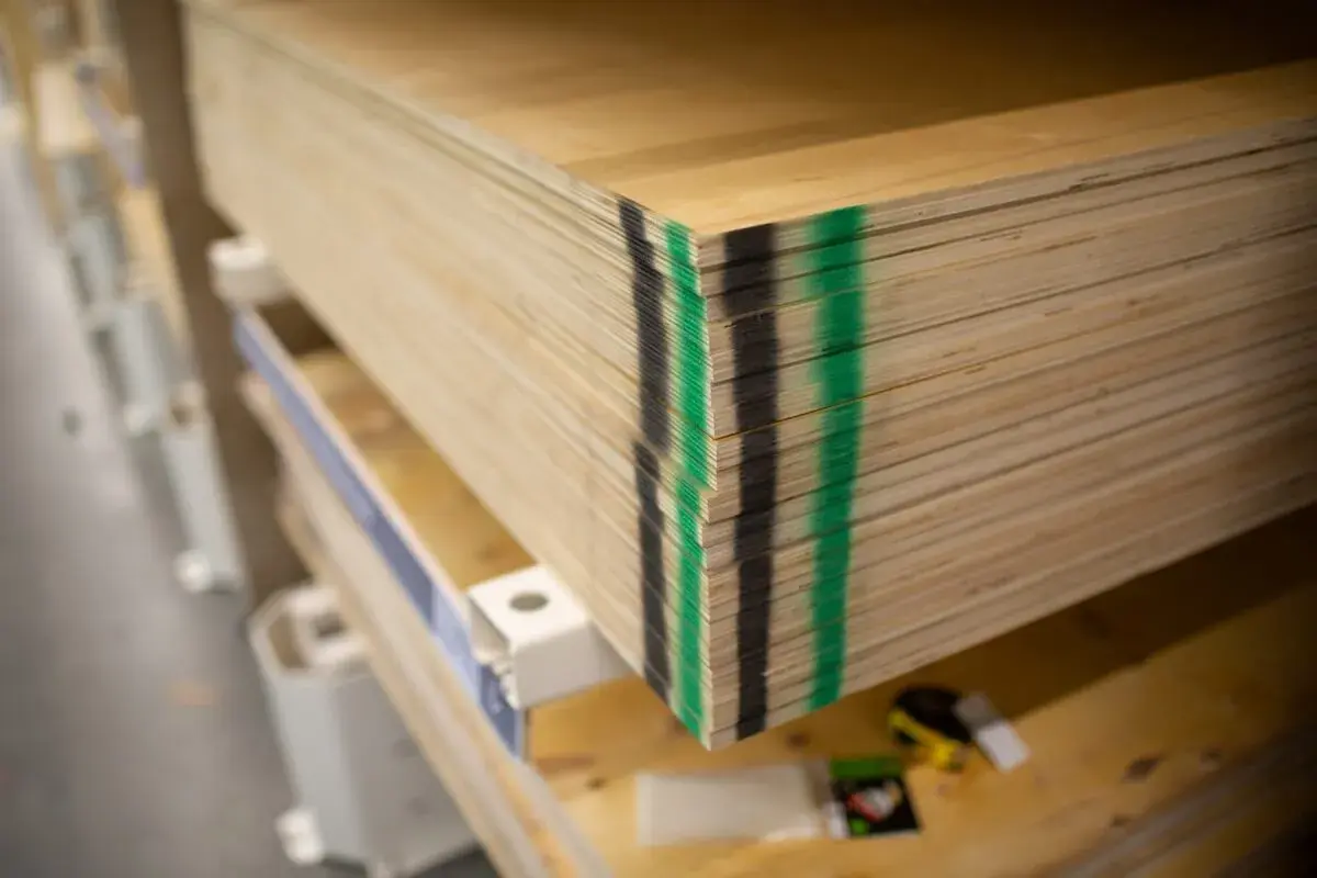 Stos płyt sklejkowych, czyli **dykta**, z zielonymi i czarnymi oznaczeniami na krawędziach, gotowy do użycia.