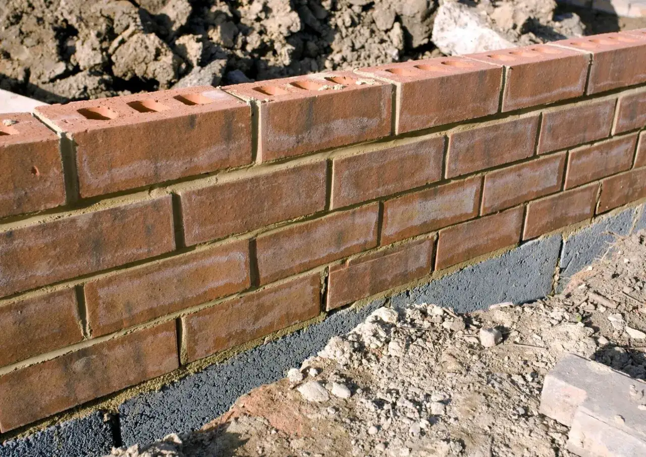 Solidna podmurówka z bloczków betonowych to świetne rozwiązanie co zamiast podmurówki pod ogrodzenie. Ceglana ściana prezentuje się okazale.