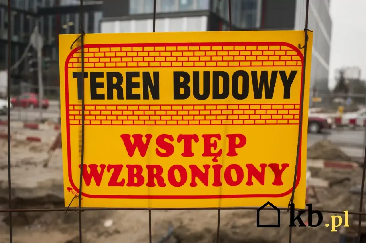 Żółta tablica informacyjna budowy z napisem 