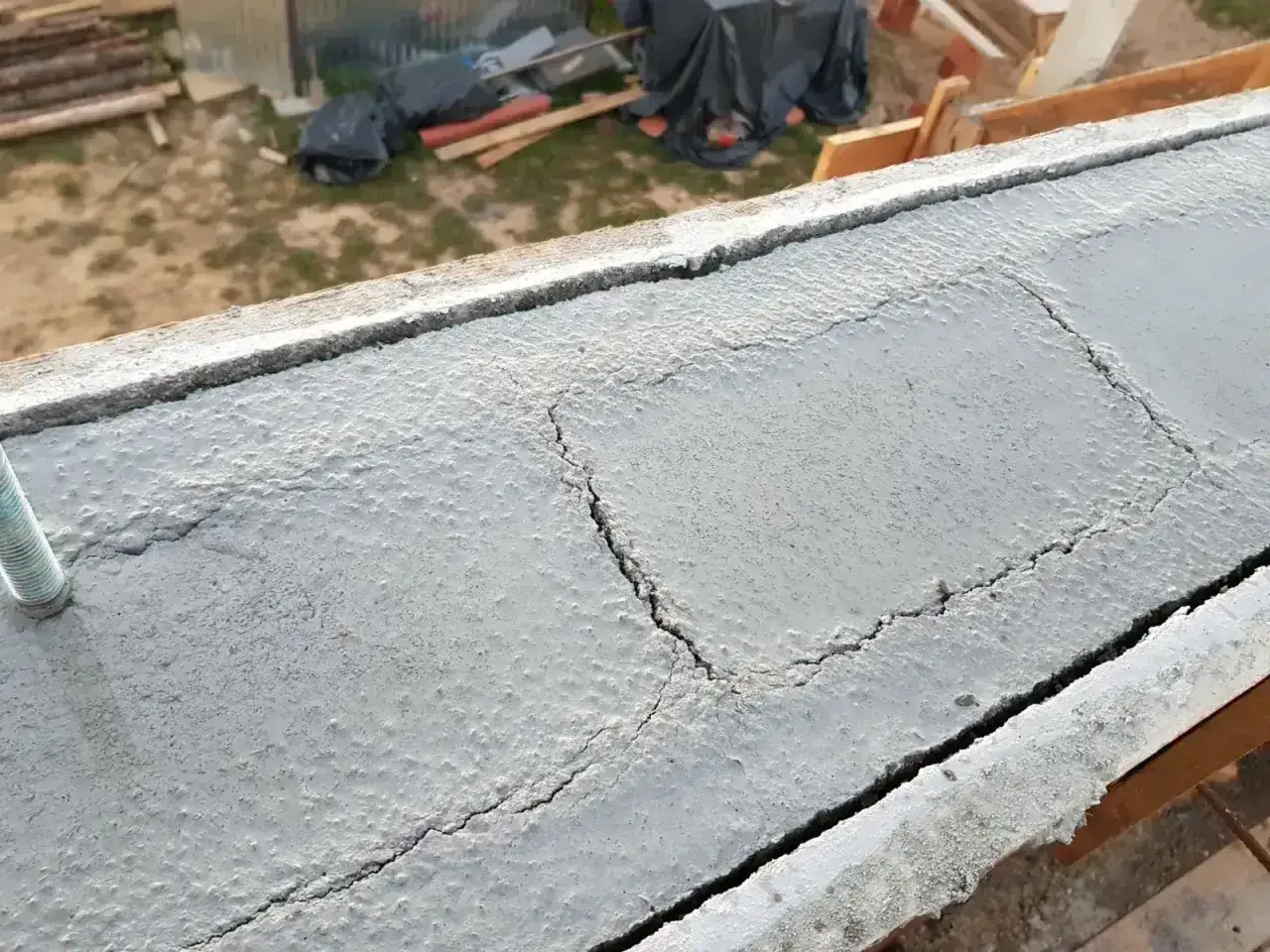 Pęknięcia na świeżym betonie wieńca budowlanego. Widać ślad po kotwie.