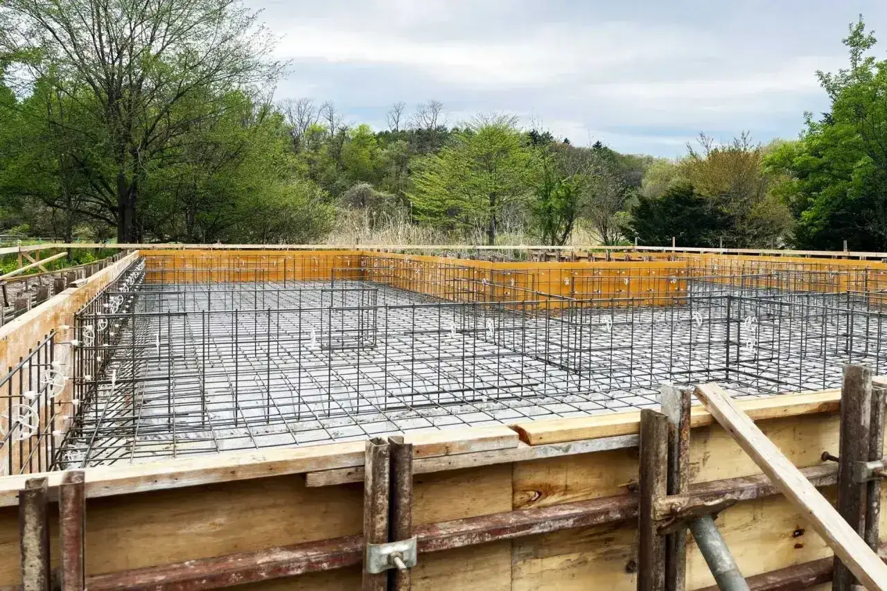 Siatka zbrojenia czeka na beton. Fundament domu w otoczeniu zieleni.